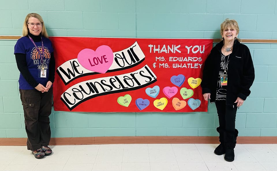 Mills' Elementary Counselors: Elise Edwards and Linda Whatley standing in front of a poster on Counselor's Appreciation Week