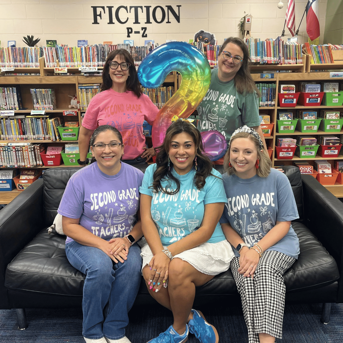 Second grade teachers posing on a couch in the library